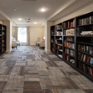 A quiet library space with bookshelves lining the walls and a seating area by the window.