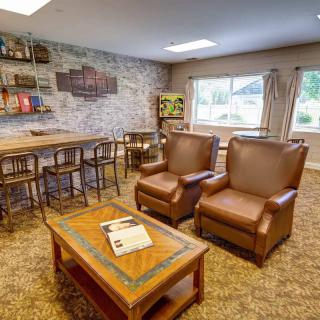 A cozy living room with leather armchairs, a wooden coffee table, and a bar counter.