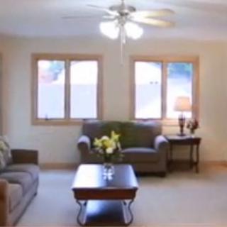 A cozy living room with sofas, a coffee table, and large windows.