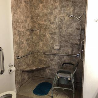 An accessible bathroom with a shower, grab bars, and a shower chair for ease of use.