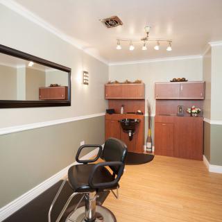 A modern hair salon with stylish decor, featuring a salon chair, large mirror, and sleek lighting.