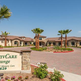 A sunny view of a building complex with palm trees and an entrance sign.