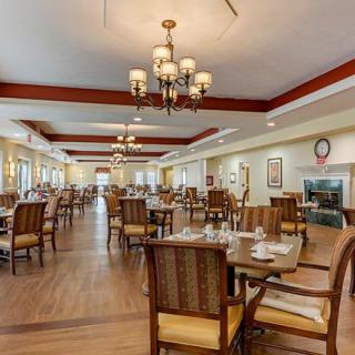 A spacious dining room with neatly arranged tables and chairs, illuminated by elegant chandeliers.
