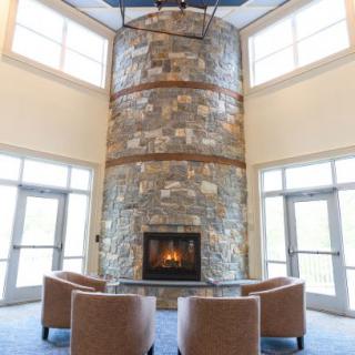 A modern interior with a tall stone fireplace and comfortable seating.
