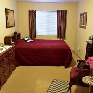 A cozy bedroom with a neatly made bed, surrounded by classic furniture and decorative artwork.