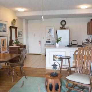 A cozy living space featuring a small kitchen and dining area with wooden furniture and decorative elements.