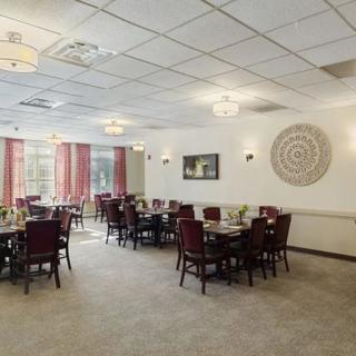 A neat and well-arranged dining room with multiple tables and chairs, featuring warm decor and ambient lighting.