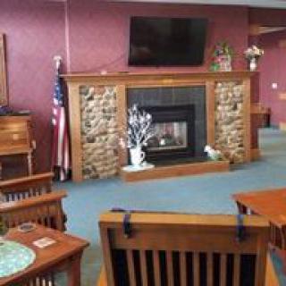A cozy living room with a stone fireplace, television, and wooden furniture.