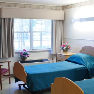 A hospital room with two beds, decorated with flowers and curtains.