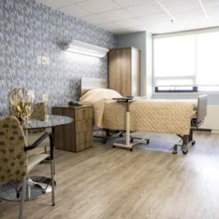 A modern and clean hospital room with a bed, chair, and window.