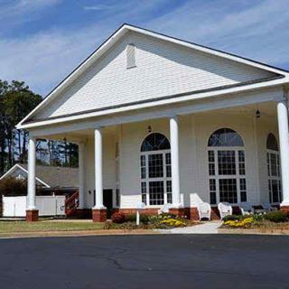 A large white building with classic columns and large windows under a clear blue sky.