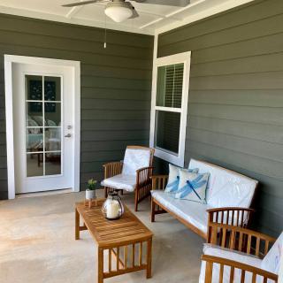 A cozy patio with wooden furniture and cushions, featuring a small table and a ceiling fan.