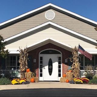 A building entrance decorated for autumn with pumpkins and hay bales.