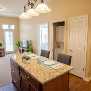 A modern kitchen with an island counter and seating, featuring a neatly set dining area.