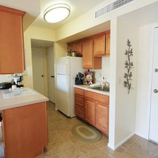 A cozy kitchen with wooden cabinets, a refrigerator, and tiled flooring.