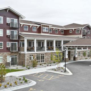 A modern residential building with multiple stories and a landscaped entrance.