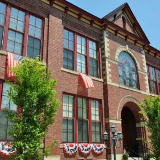 A historic brick building adorned with decorative flags and surrounded by trees.