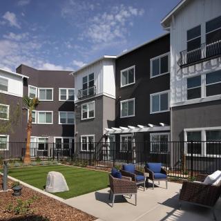 A modern apartment complex with outdoor seating and landscaped areas.