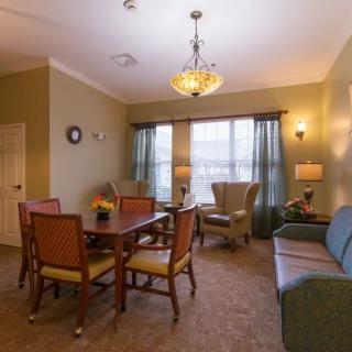 A cozy living and dining area with traditional furnishings, including a dining table, chairs, a sofa, and a chandelier.