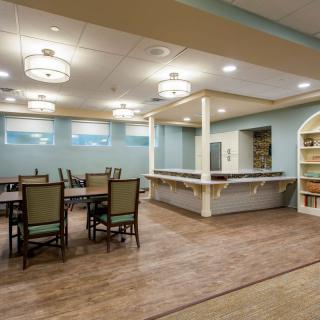 A spacious dining area with tables and chairs, featuring elegant lighting and warm decor.