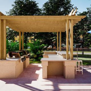 An outdoor grill area with a pergola, featuring seating and barbecue stations in a park-like setting.