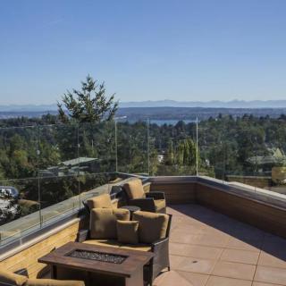 A scenic terrace with comfortable seating offers a stunning view of the ocean and surrounding greenery.