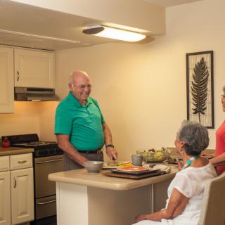 A family enjoys a conversation in the kitchen while preparing a meal.