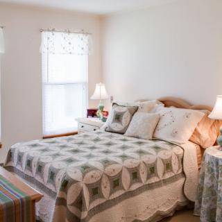 A cozy bedroom with a quilt-covered bed and soft lighting.