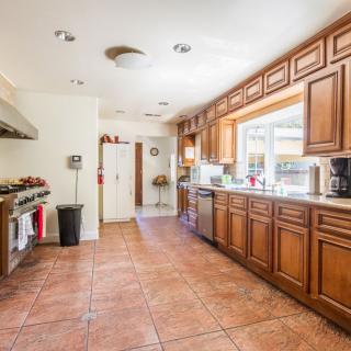 A spacious and modern kitchen with wooden cabinets and tiled flooring.