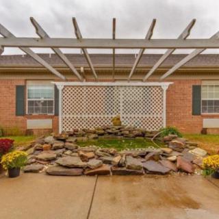 A backyard patio features a pergola and a decorative stone arrangement, creating an inviting outdoor space.