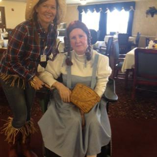 Two people dressed in Wizard of Oz costumes, with one as Dorothy sitting in a wheelchair and the other as the Scarecrow.