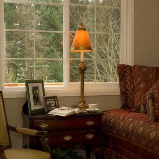 A cozy living room corner with a lamp, side table, and sofa near a window.