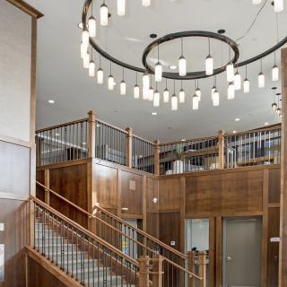 A modern interior with a wooden staircase and a circular chandelier.