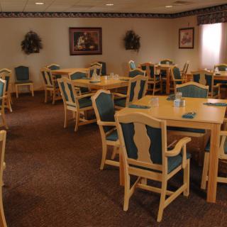 An empty dining room with wooden tables and chairs arranged neatly.