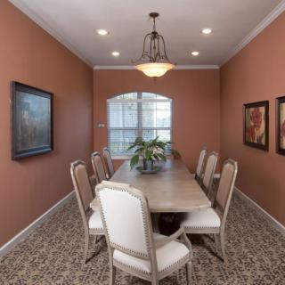 A well-decorated dining room featuring a long table, upholstered chairs, and wall art.