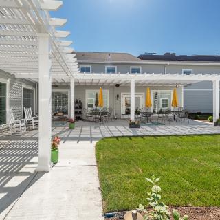 A spacious backyard featuring a pergola-covered patio with outdoor seating and a well-maintained lawn.