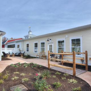 A single-story building with a pathway and landscaped garden area on a sunny day.