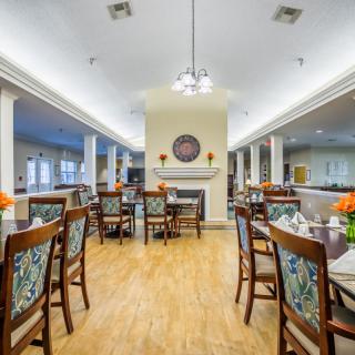 A well-lit dining area with wooden tables and chairs, decorated with floral patterns.