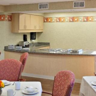 A cozy dining area with neatly arranged tables and chairs, featuring a counter in the background.