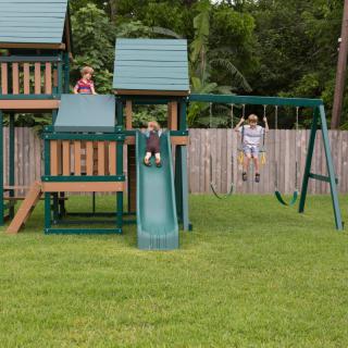 Children enjoying a day at the playground, with one on the swing and another sliding down the slide.