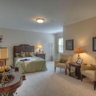 A cozy and elegantly furnished bedroom featuring a large bed, chairs, and warm lighting.