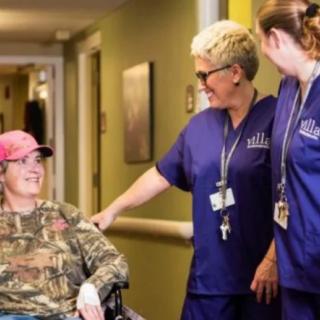 Nurses interacting with a patient in a wheelchair at a healthcare facility.