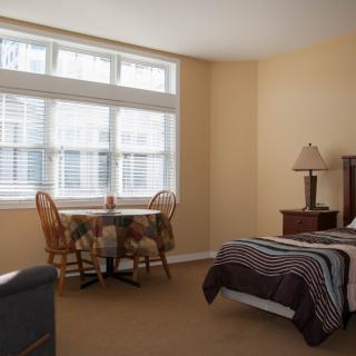 A cozy bedroom with a bed, table, and large window.