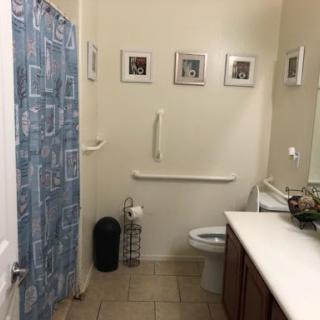 A view of a clean and organized bathroom featuring a shower, toilet, and decorative elements.
