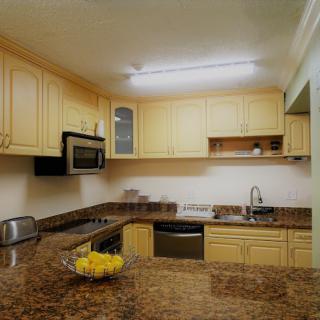 A modern kitchen with wooden cabinets, granite countertops, and stainless steel appliances.