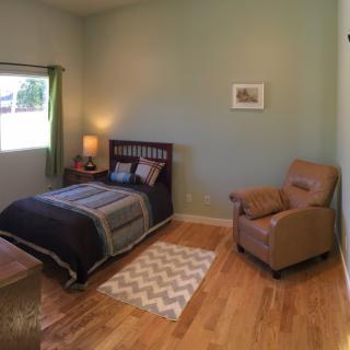 A cozy bedroom with a single bed and an armchair.