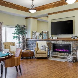 A cozy living room with a fireplace and television, featuring comfortable seating and elegant decor.
