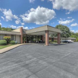 A building with a covered entrance and parking area under a partly cloudy sky.