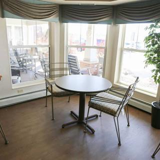 A cozy dining area with a round table and four chairs by large windows.