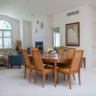 A modern dining area with a wooden table and six chairs in a well-lit, open living space.
